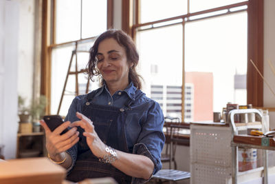 Female artist using mobile phone in workshop