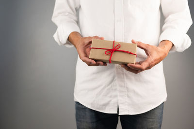 Midsection of man holding box against white background