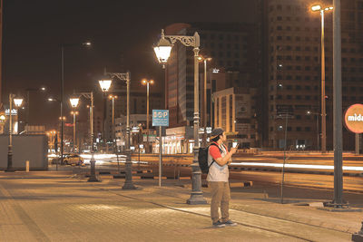 Rear view of man standing on illuminated street at night