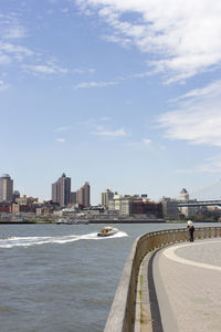 Bridge over sea by buildings in city against sky