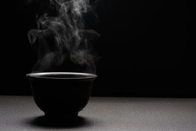 Close-up of coffee cup on table against black background