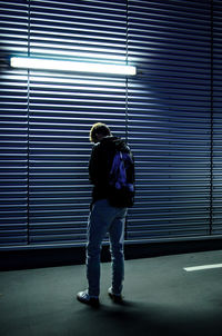 Rear view of man standing against closed shutter