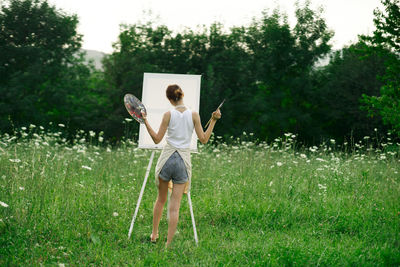 Rear view of woman with umbrella standing on field