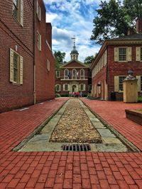 Cobblestone street in city against sky