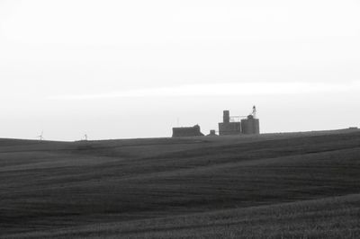 Lighthouse on field against clear sky