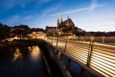 Bridge over river by buildings against sky in city