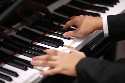 Cropped hands of woman playing piano