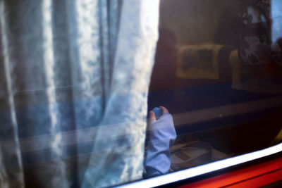 Cropped image of hand seen through train window