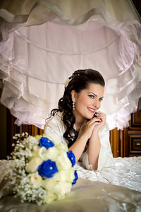 Portrait of young woman sitting on bed