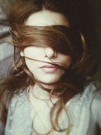 Close-up of a young woman with brown hair over face