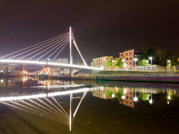 Cityscape with modern concrette illumanite bridge at night and boats and cars in the background