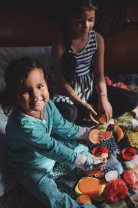 High angle view of happy girl sitting on table at home