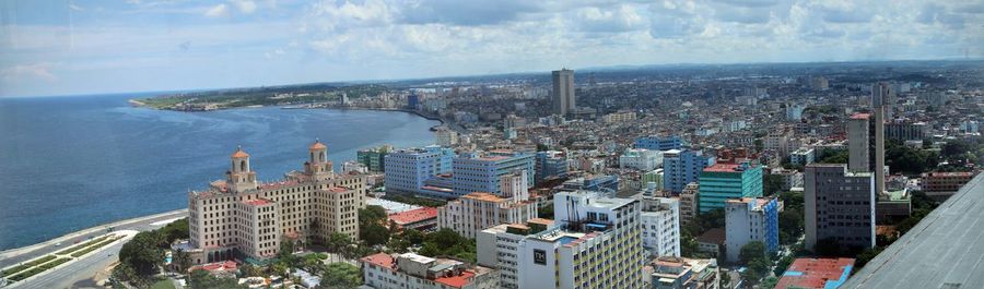 Panoramic view of residential district by sea against cloudy sky