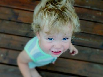 Portrait of cute boy smiling while standing on wooden floor