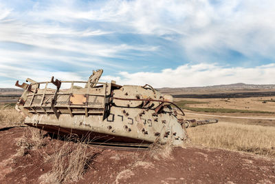 Abandoned boat on field against sky