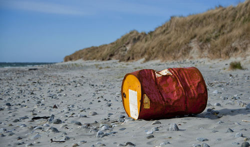 Oil barrel on beach against sky