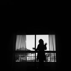 Silhouette of woman looking out of window