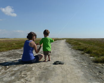 Full length of boy standing on grass with his mom playing with a kite