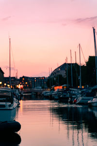 Sailboats moored at harbor against sky during sunset