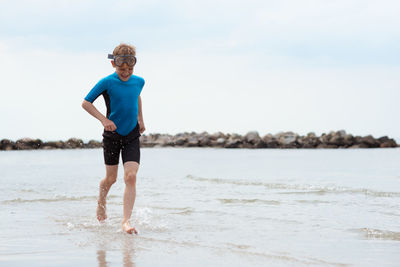 Full length of man standing on beach against sky