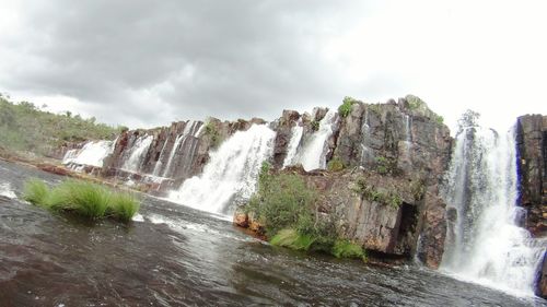 Scenic view of waterfall against sky