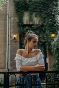 Woman looking away while standing by railing