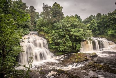 Scenic view of waterfall against sky