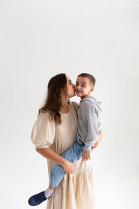 Portrait of smiling mother and daughter against white background