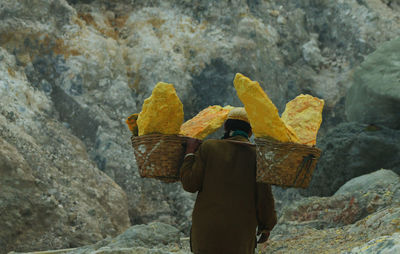 Rear view of man carrying rocks