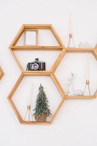 Pine wood hexagonal shelves on the wall with a variety of decor. christmas tree, retro camera