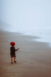 Boy standing at beach against sky