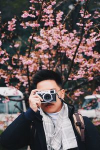 Young man with camera standing at park during winter