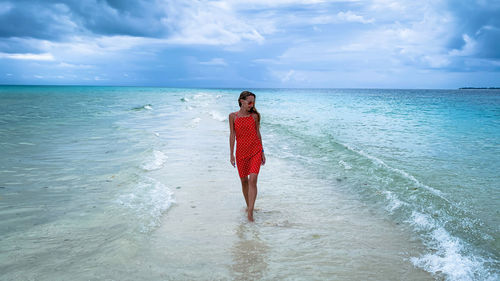 Rear view of woman standing at beach against sky in zanzibar tanzania 