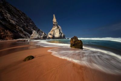 Rock formations on beach against sky