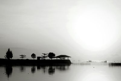 Silhouette people on pier by sea against sky