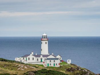 Lighthouse by sea against sky