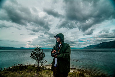 Young man standing in sea against sky