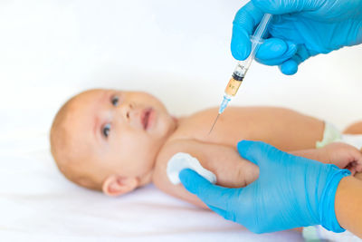 Hands of doctor with syringe giving vaccination to baby