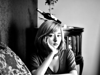 Portrait of young woman looking away while sitting at home