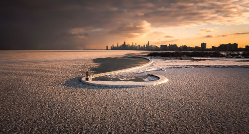 Chicago skyline aerial photograph of a hook shaped pier at sunset with frozen ice and snow.