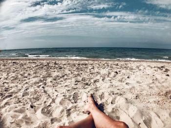 Low section of man relaxing on at sandy beach