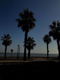 Silhouette palm trees on beach against clear sky