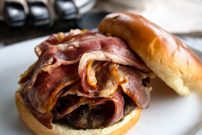Many strips of bacon on a burger on a plate close up