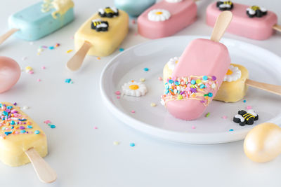 Cakesicles decorated for spring and easter scattered about with two on a plate.