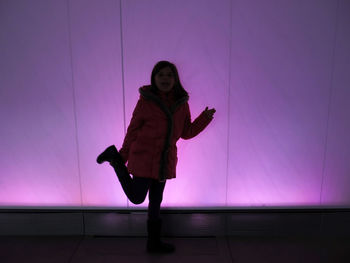 Full length of woman standing against pink wall