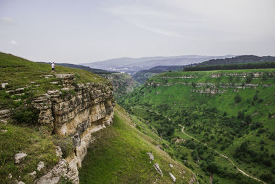 Man standing on cliff by mountains