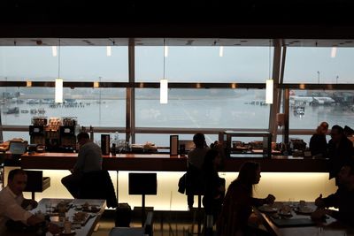 People sitting at airport against sky in city