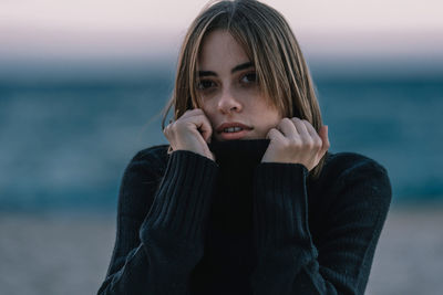 Portrait of young woman standing in sea during winter