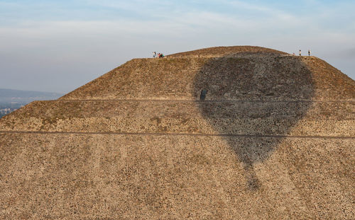 Man feeding horse against sky