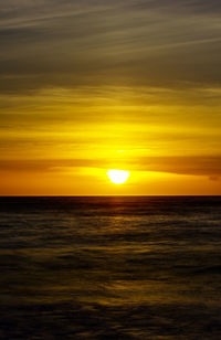 Scenic view of sea against dramatic sky during sunset